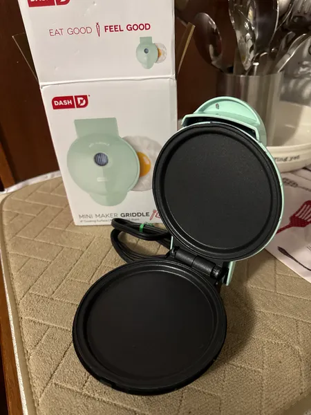 Golden Belgian waffles beside a stainless steel waffle maker